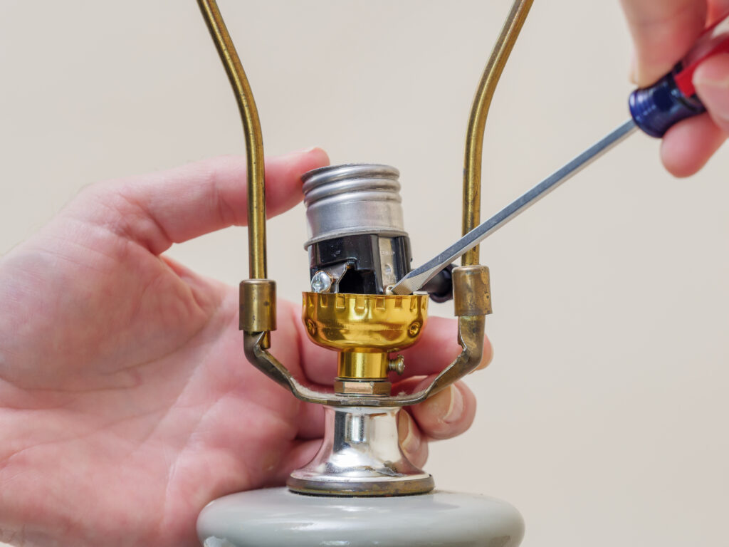 Des mains avec un tournevis réparent la douille d'une lampe de le cadre d'un atelier de formation à l'électrification de luminaire dispensé par EAD formations