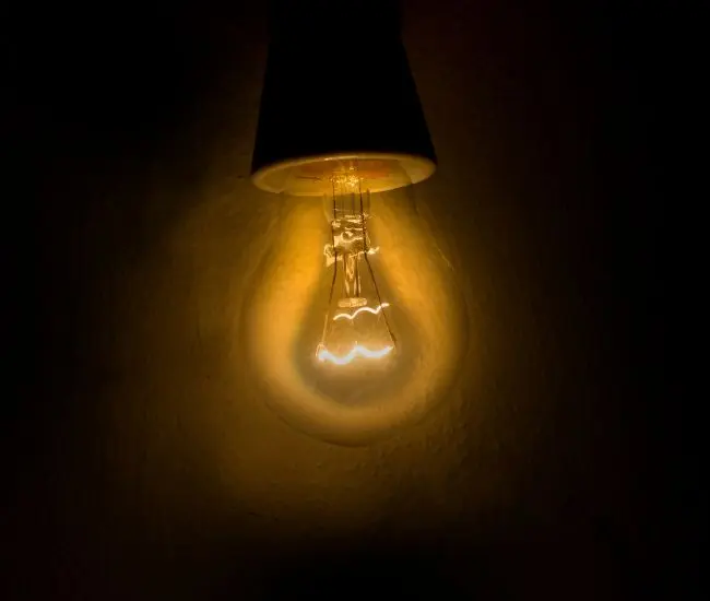 Ampoule allumée diffusant une lumière chaude dans l’obscurité, symbole des enjeux de sécurité électrique dans la fabrication de luminaires.