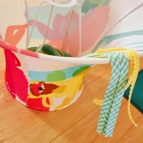 Abat-jour coloré aux motifs vifs, accompagné de rubans décoratifs verts et jaunes créés par un stagiaire.