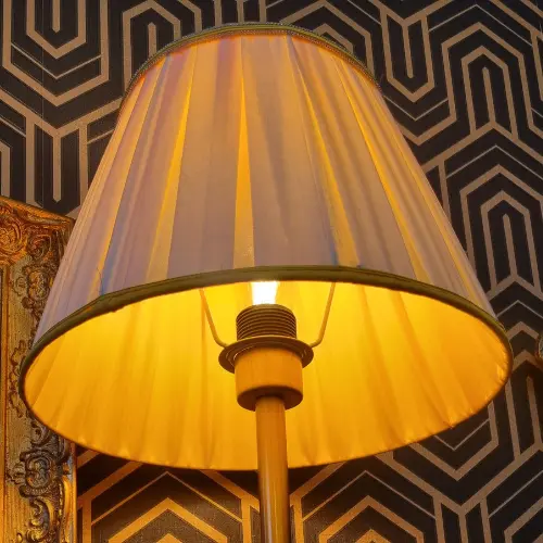 Abat-jour cylindrique éclairé de l’intérieur, révélant un plissé soigné et des finitions nettes.