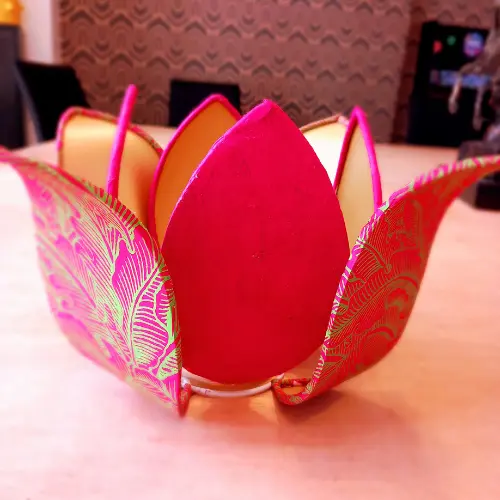Abat-jour en forme de fleur aux pétales rose vif et motifs dorés, créé par un stagiaire.