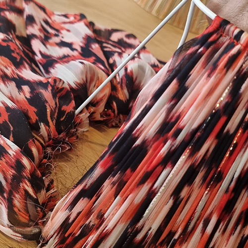 Tissu plissé aux motifs rouges et noirs fixé sur la carcasse d’un abat-jour, illustrant une étape de montage minutieuse.