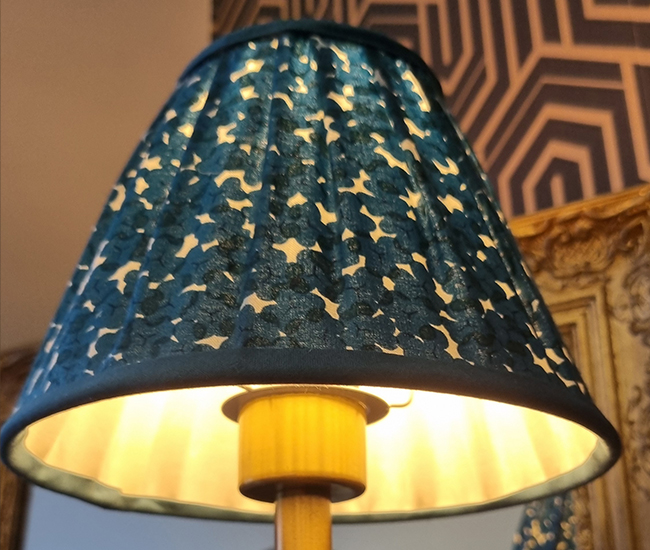 Abat-jour plissé façonné en atelier, illustrant l’apprentissage des techniques artisanales.